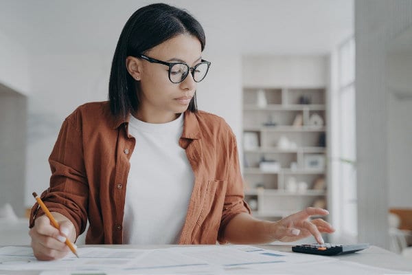 Serious woman in glasses manage household budget count financial expenses for saving money at home Woman Calculating